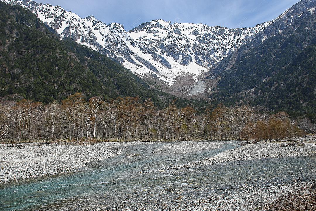 Montanhas cobertas de neve ao fundo e lago claro na cena de inverno em Kamikochi, Japão