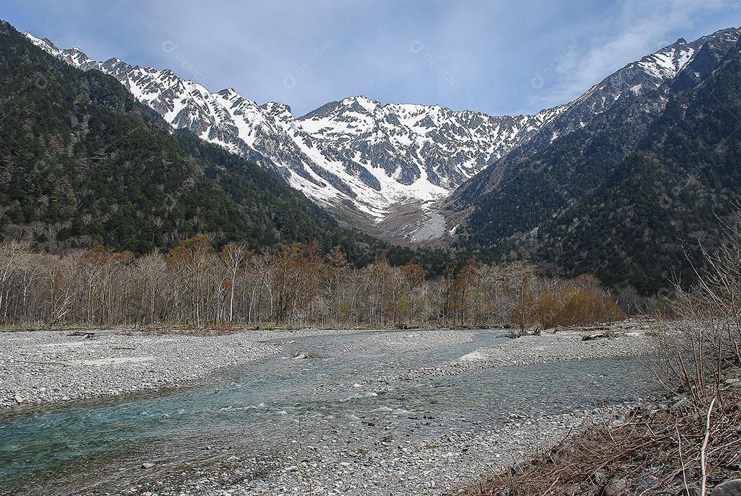 Montanhas cobertas de neve ao fundo e lago claro na cena de inverno em Kamikochi, Japão