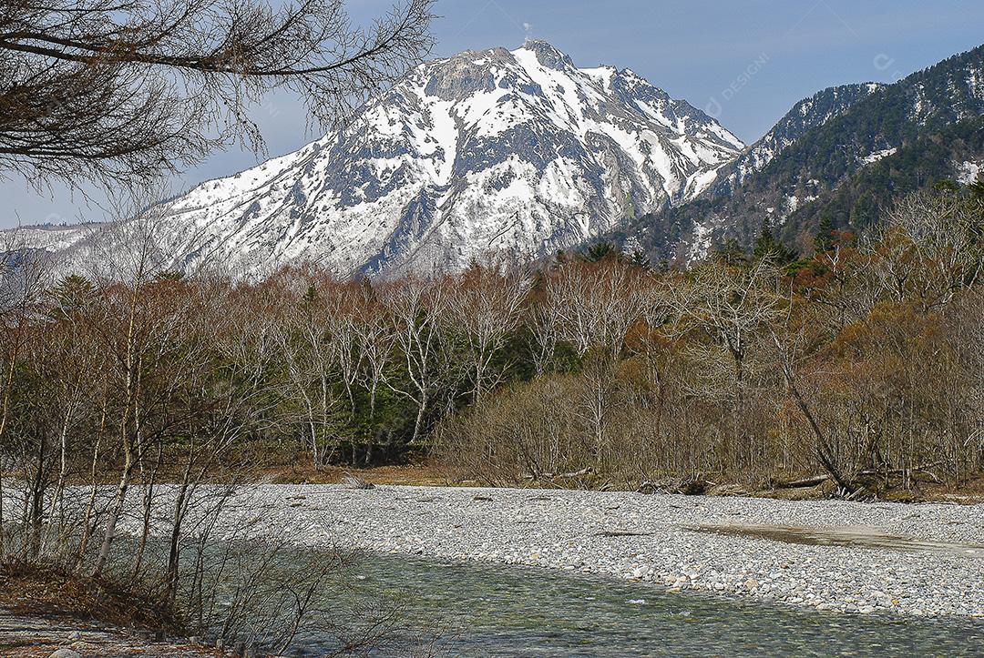 Montanhas cobertas de neve ao fundo e lago claro na cena de inverno em Kamikochi, Japão