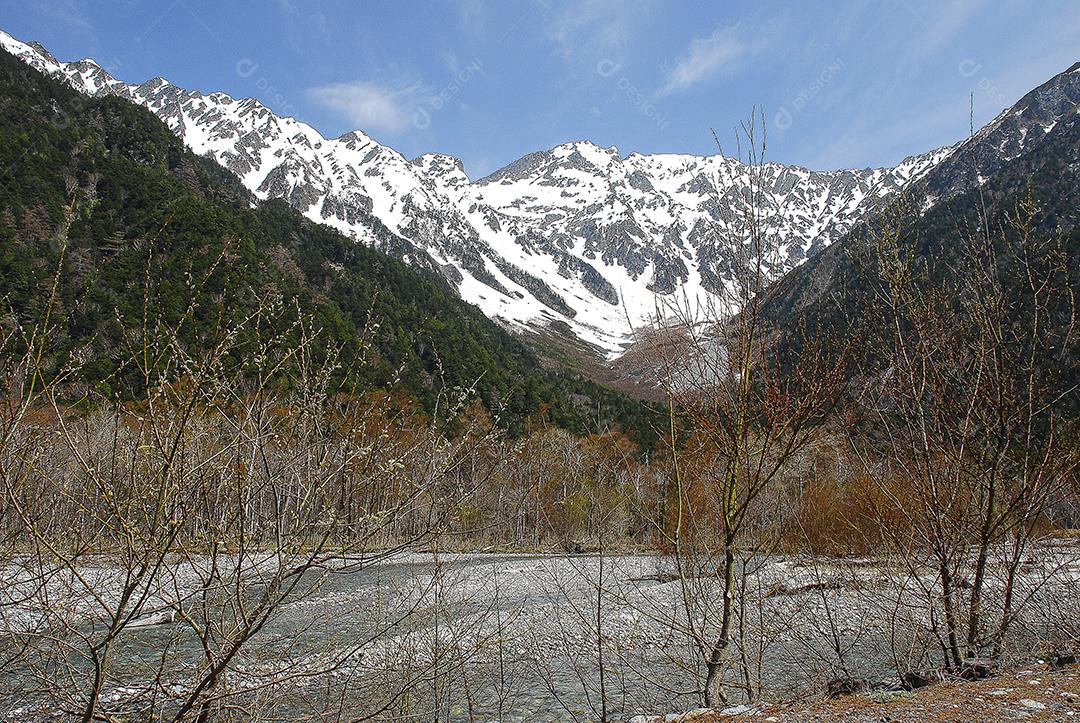 Montanhas cobertas de neve ao fundo e lago claro na cena de inverno em Kamikochi, Japão