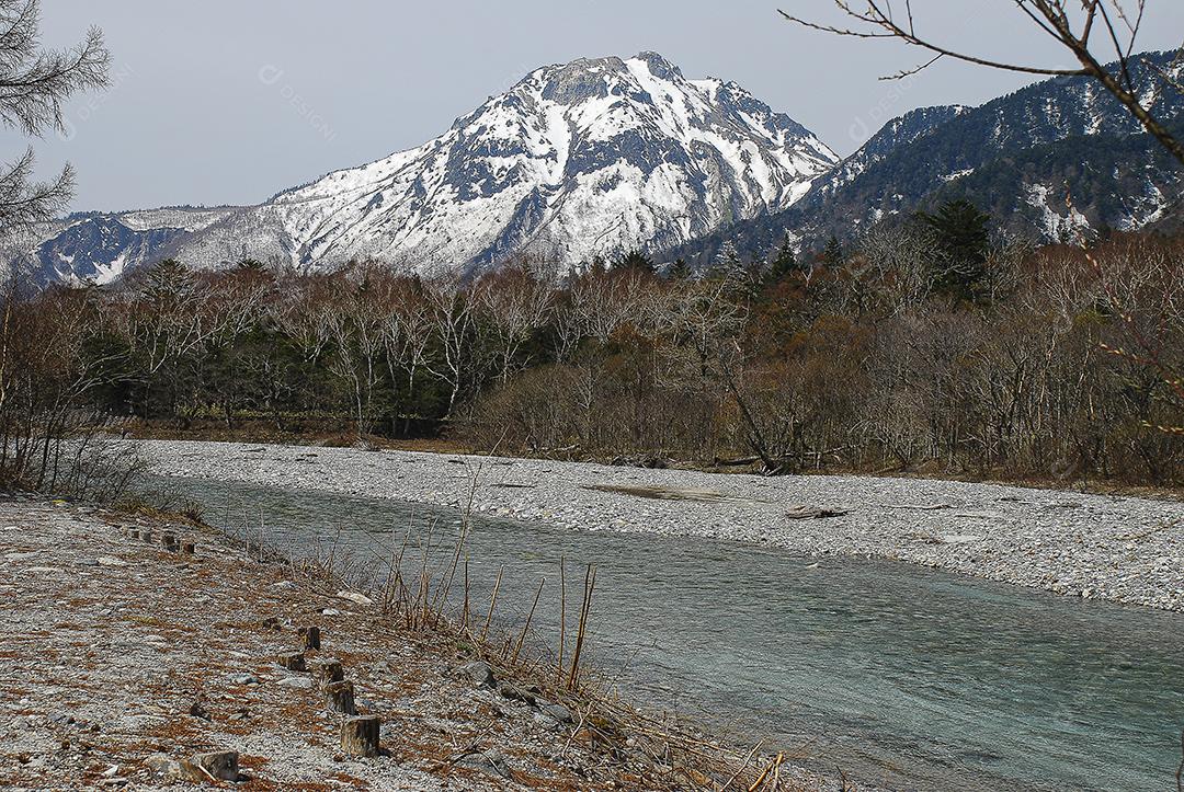 Montanhas cobertas de neve ao fundo e lago claro na cena de inverno em Kamikochi, Japão