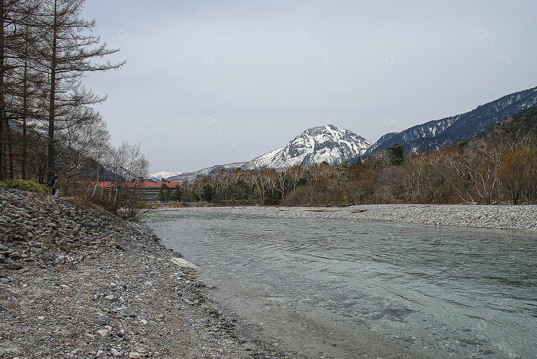 Montanhas cobertas de neve ao fundo e lago claro na cena de inverno em Kamikochi, Japão