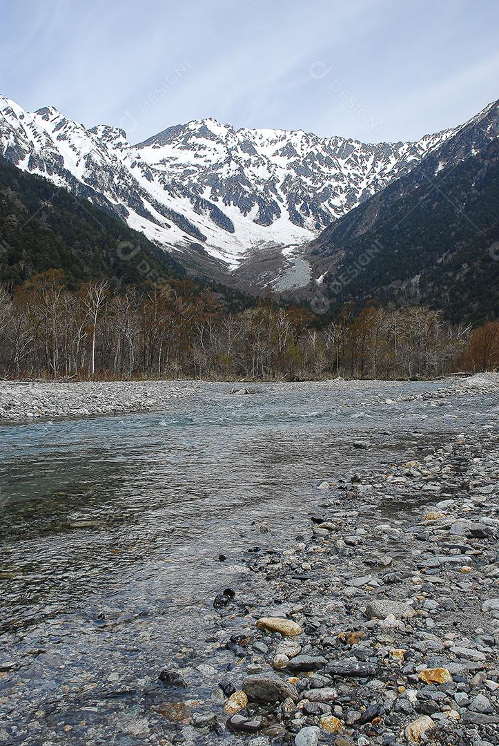 Montanhas cobertas de neve ao fundo e lago claro na cena de inverno em Kamikochi, Japão