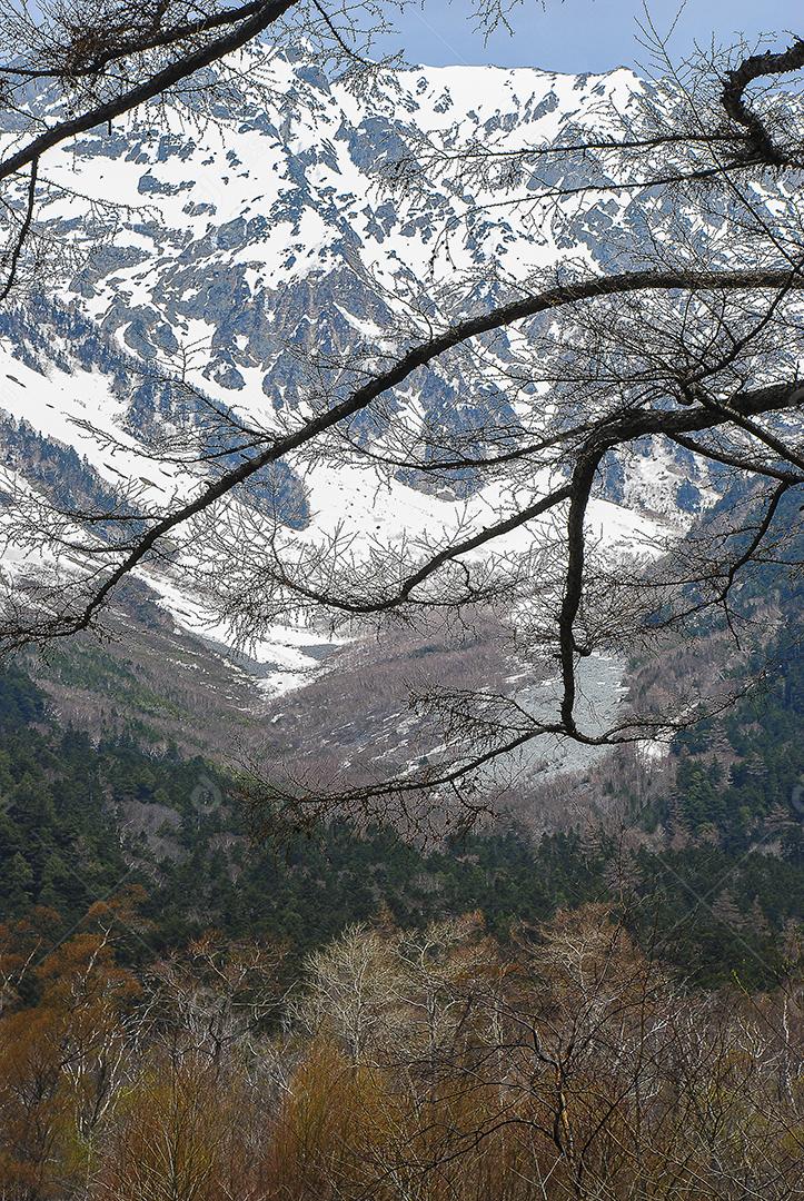 Montanhas cobertas de neve ao fundo e lago claro na cena de inverno em Kamikochi, Japão