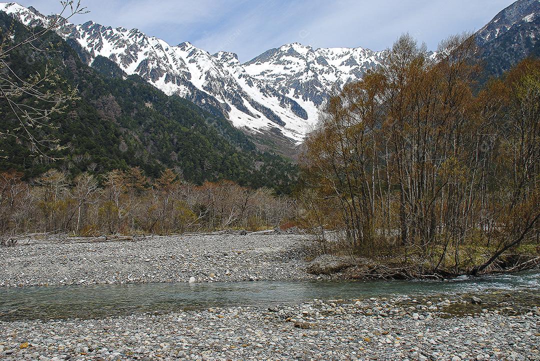 Montanhas cobertas de neve ao fundo e lago claro na cena de inverno em Kamikochi, Japão