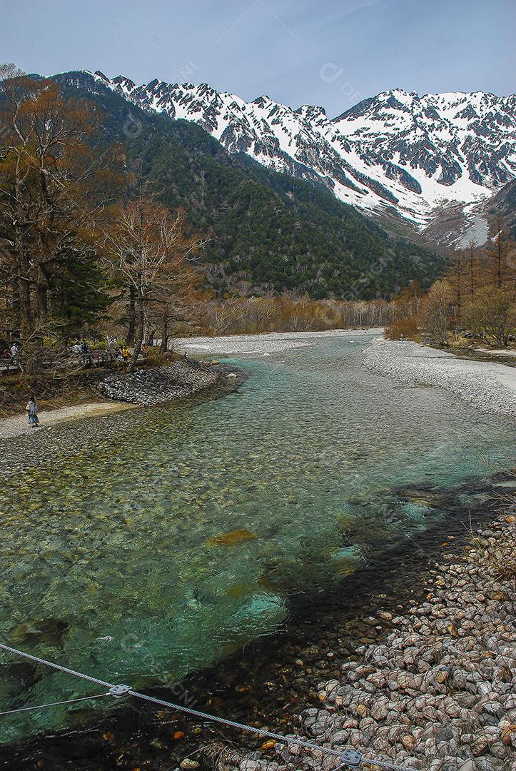 Montanhas cobertas de neve ao fundo e lago claro na cena de inverno em Kamikochi, Japão