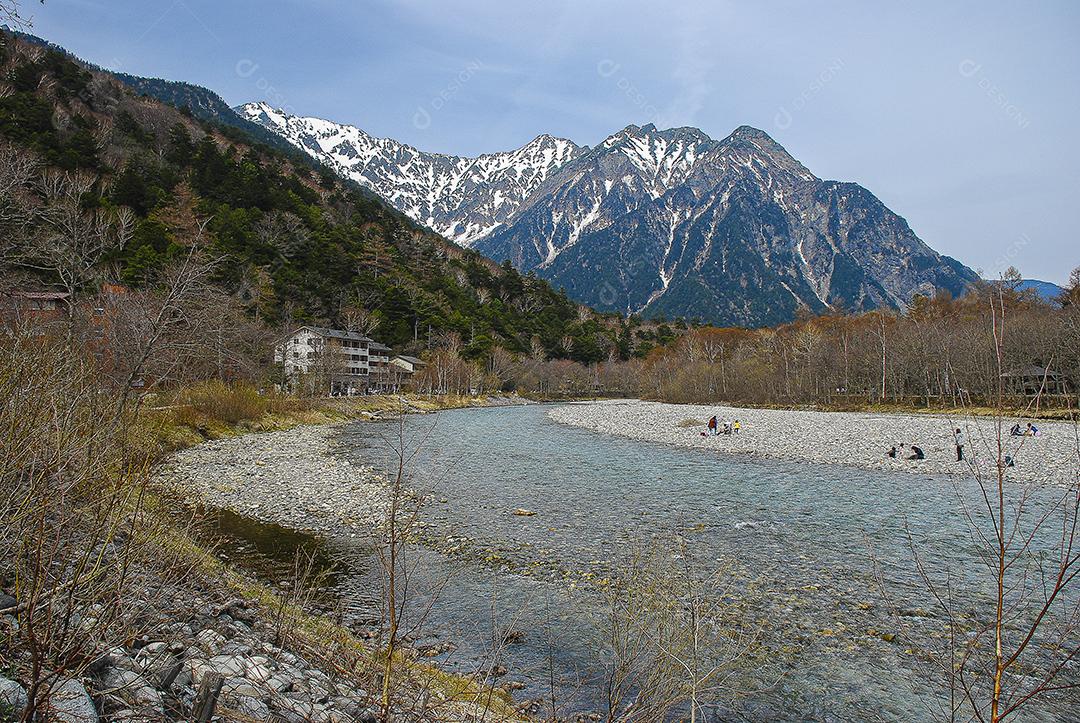 Montanhas cobertas de neve ao fundo e lago claro na cena de inverno em Kamikochi, Japão