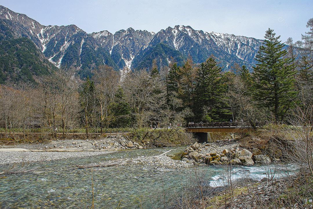 Montanhas cobertas de neve ao fundo e lago Kamikochi, Japão