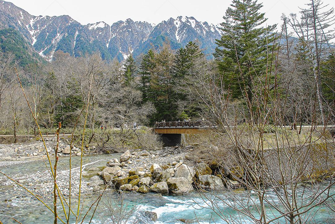 Montanhas cobertas de neve ao fundo e lago Kamikochi, Japão