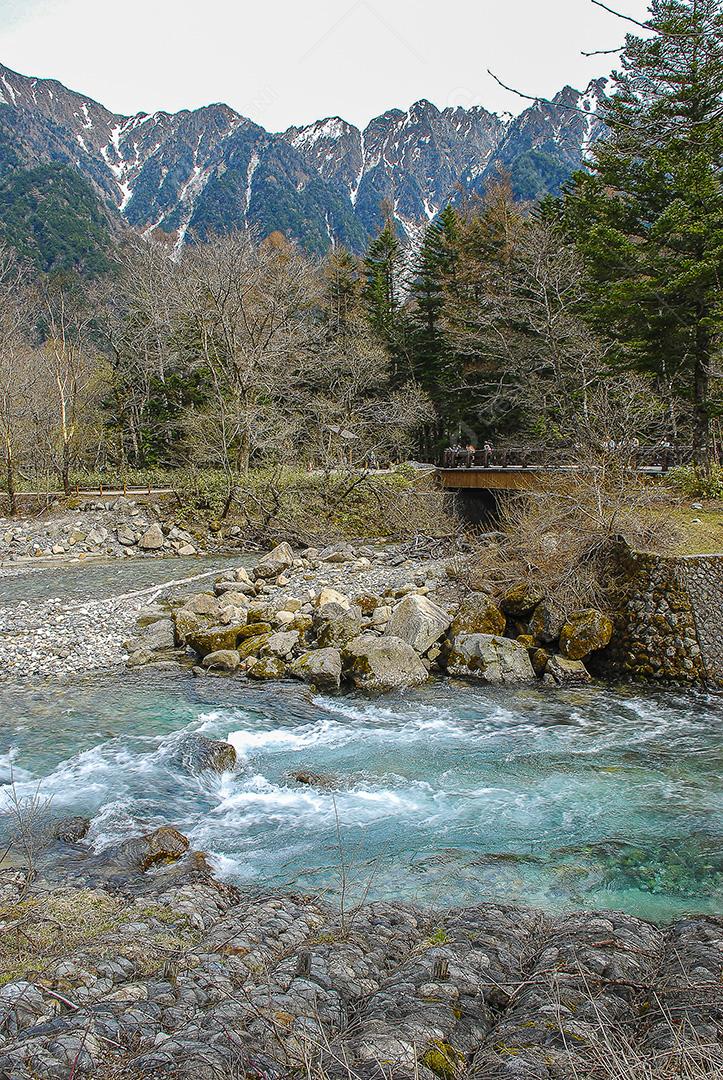 Montanhas cobertas de neve ao fundo e lago Kamikochi, Japão