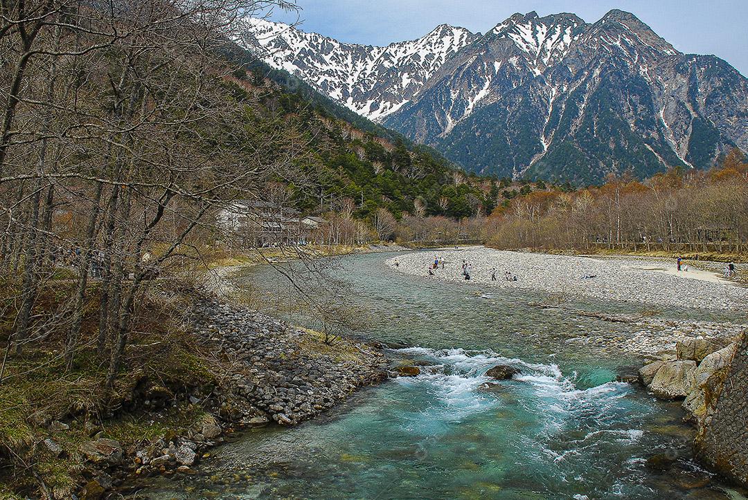 Montanhas cobertas de neve ao fundo e lago Kamikochi, Japão