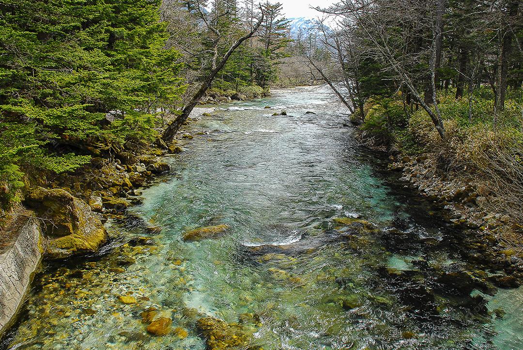 Montanhas cobertas de neve ao fundo e lago Kamikochi, Japão