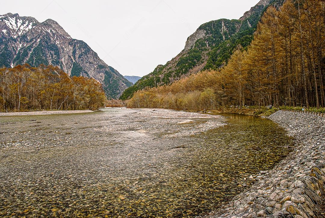 Montanhas cobertas de neve ao fundo e lago Kamikochi, Japão