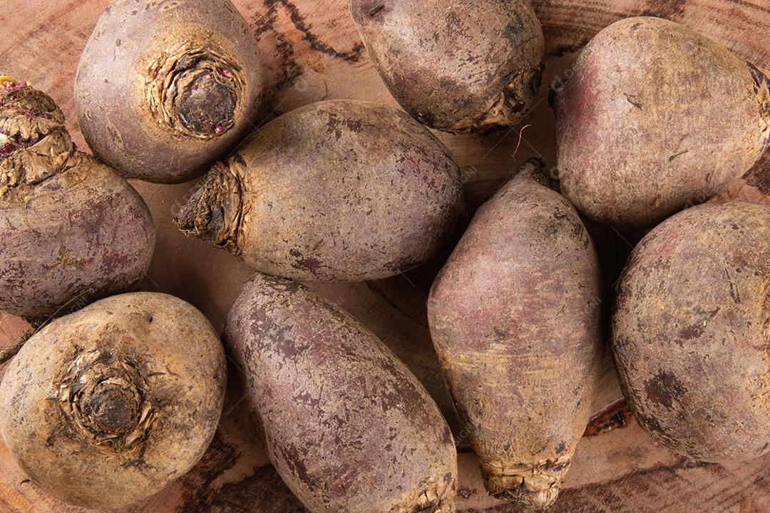 Pilha de beterrabas em tábua de madeira e fundo rústico. Vista superior