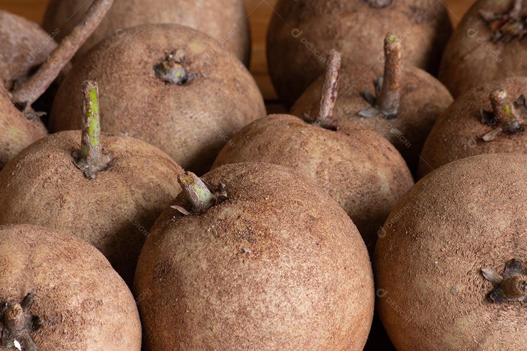 Sapodillas fruta exposta em cesta sobre mesa e fundo verde