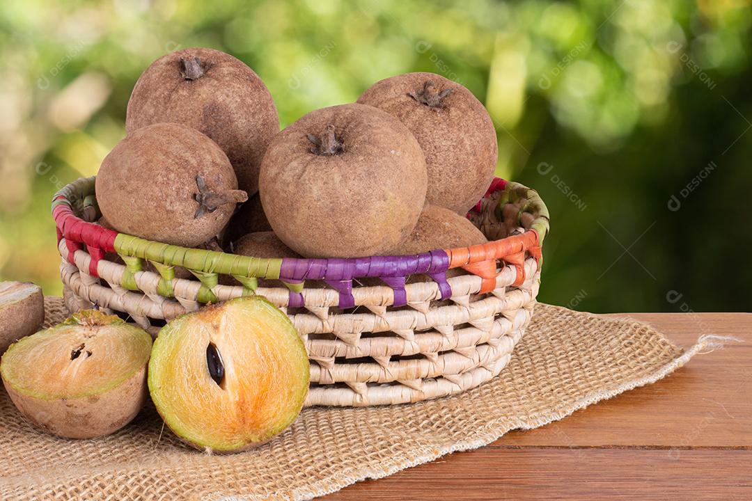 Fruta sapodilla exposta em cesta em mesa de madeira com borrado