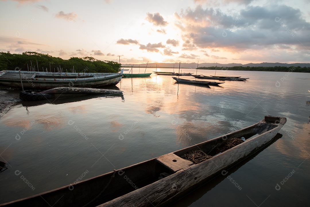 Paisagem com pôr do sol com canoas de pesca na beira do rio
