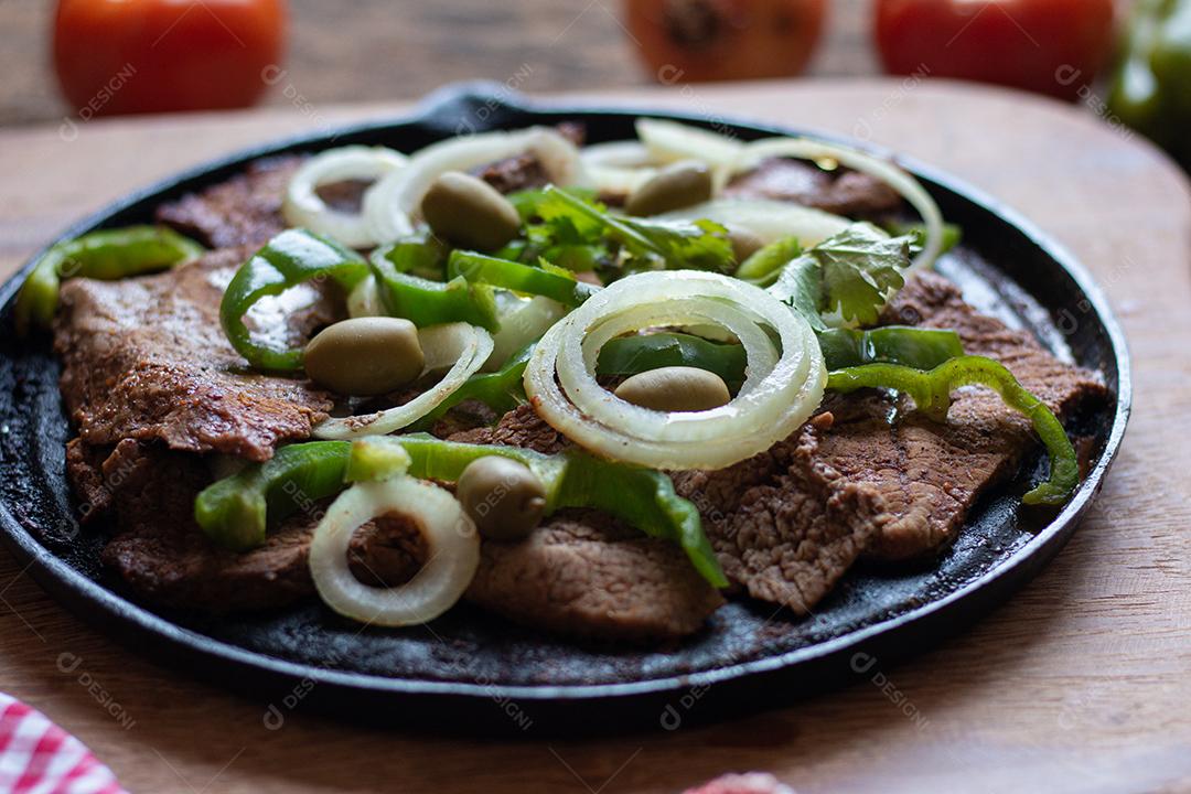 Carne frita na placa de ferro com fundo de madeira rústica