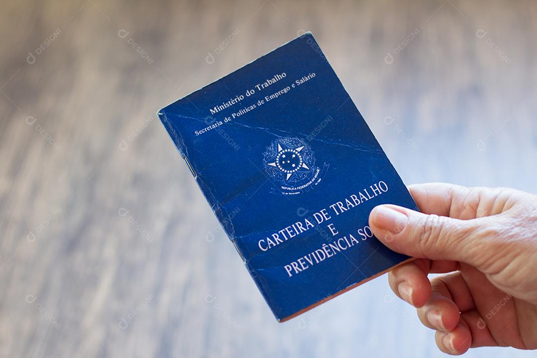 Mão segurando carteira de trabalho brasileira