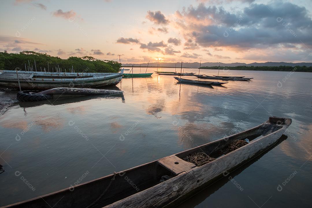 Paisagem com pôr do sol com canoas de pesca na beira do rio