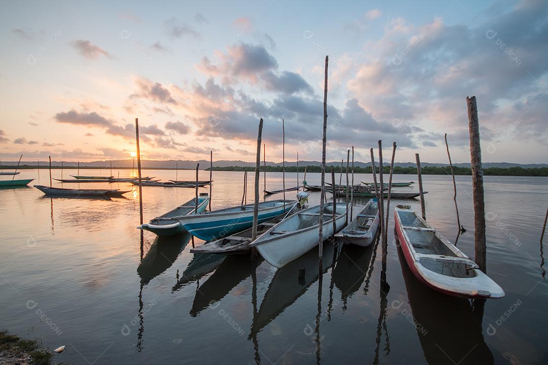 Paisagem com pôr do sol com canoas de pesca na beira do rio