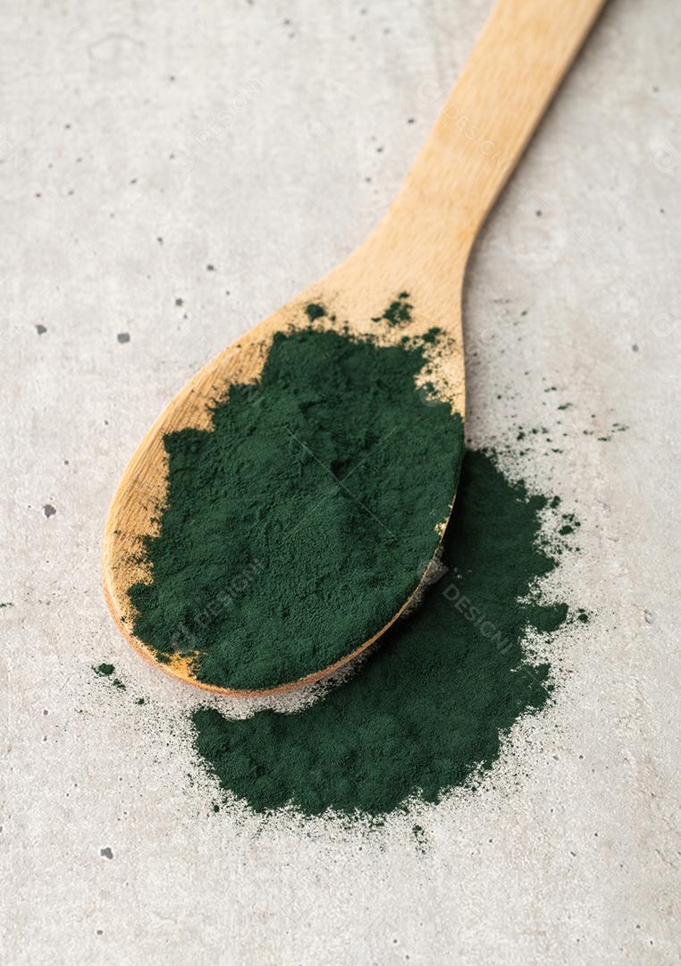 Pó de algas Spirulina em uma colher sobre a mesa de madeira