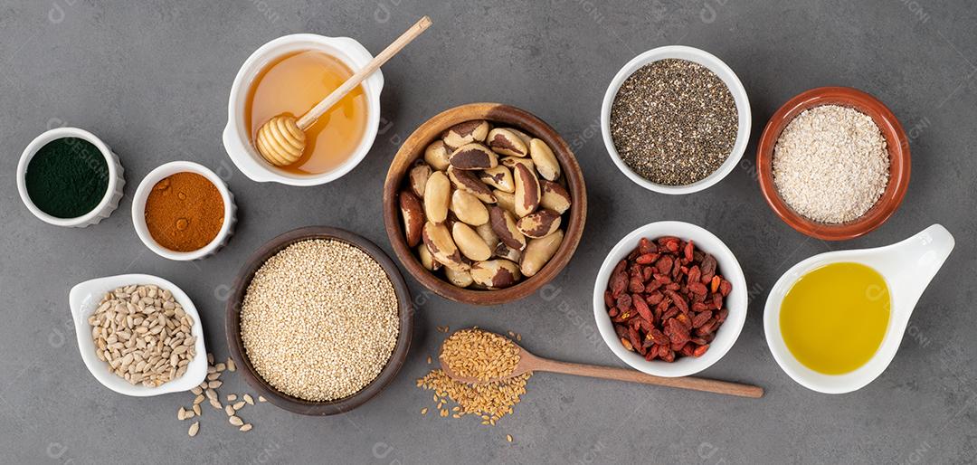 Superalimentos variados em colheres sobre fundo de pedra. Chia, quinoa, aveia, linhaça