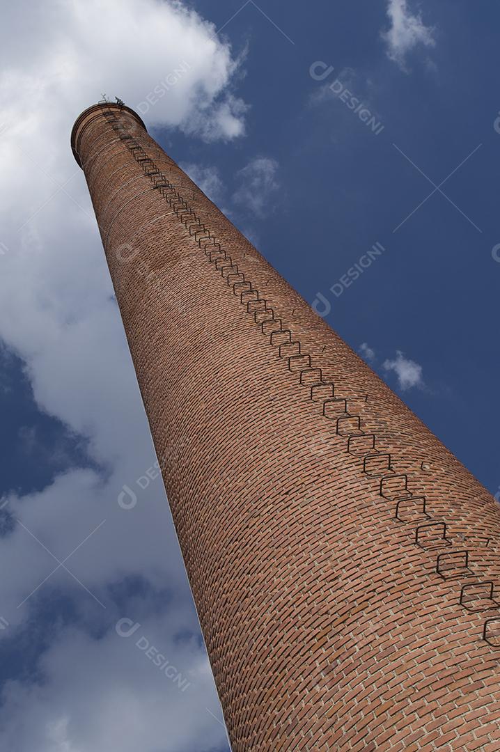 Chaminé da indústria antiga com nuvens e céus azuis