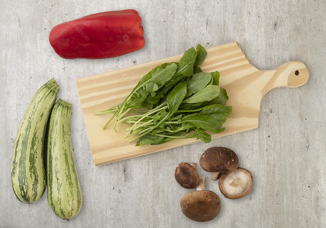 Legumes, cogumelos e ingredientes de salada sobre a mesa de madeira.