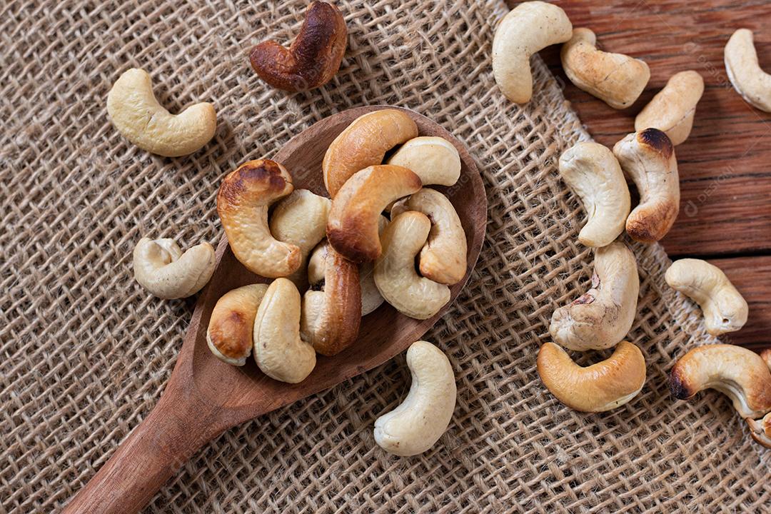 Nozes saborosas de caju em colher de pau na mesa de madeira