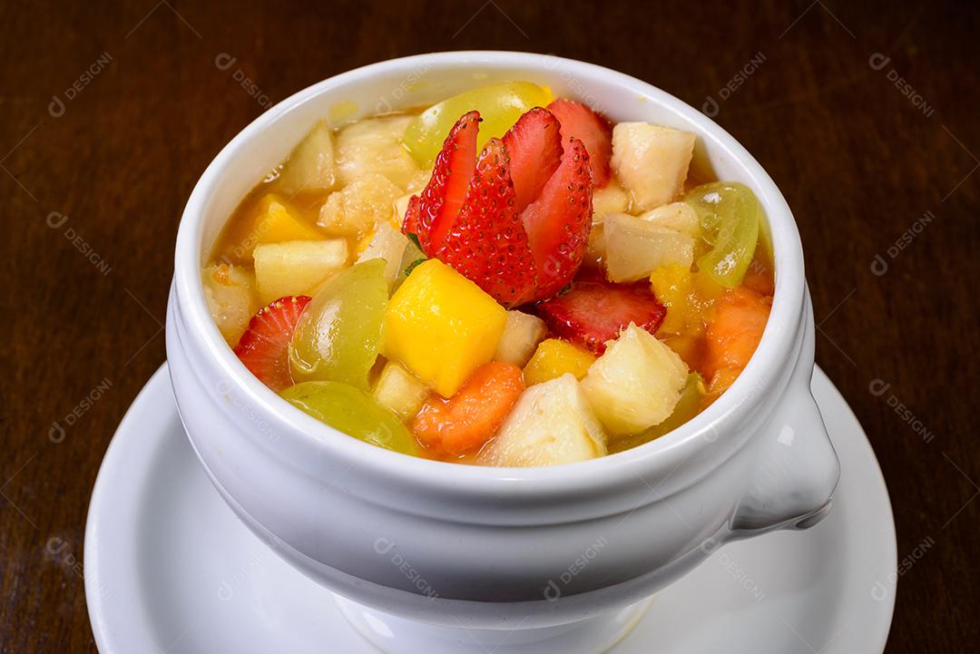 Salada de frutas com morango, uva verde, manga e abacaxi Servido em uma tigela branca.