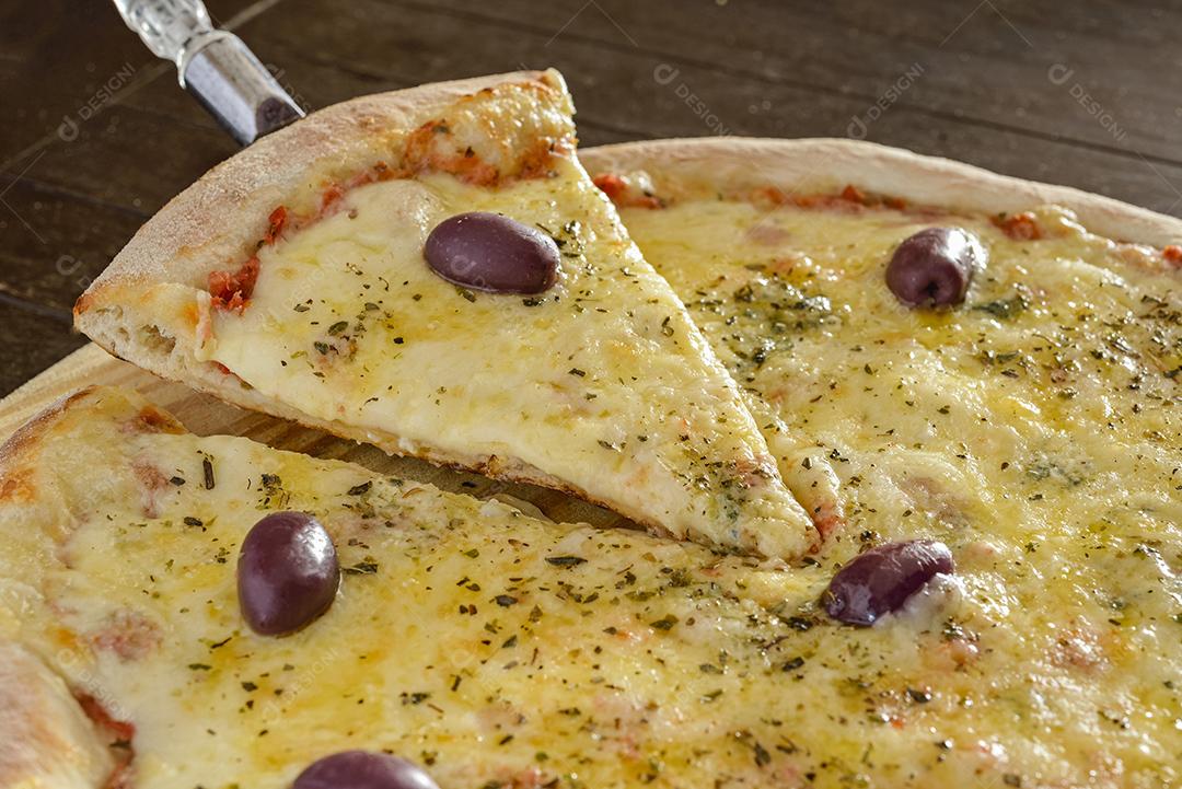 Pizza de queijo com azeitonas em close-up de pá de madeira.