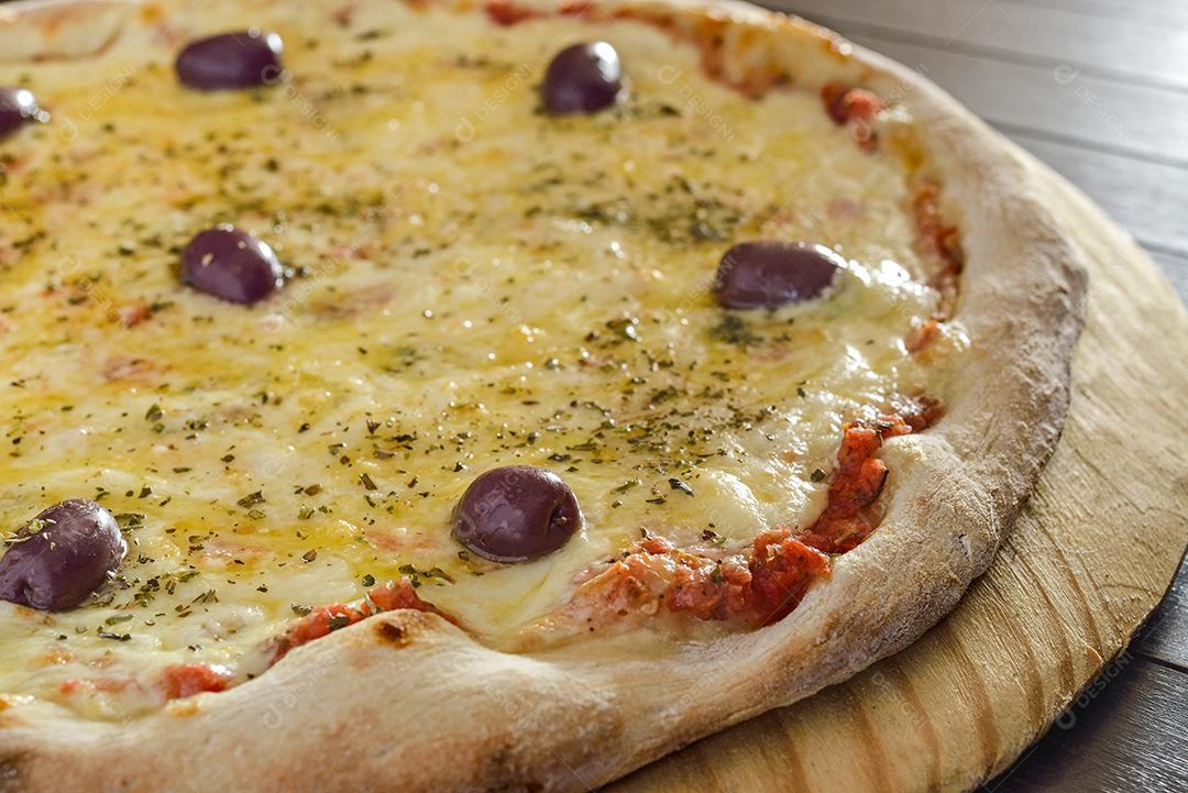 Pizza de camarão com azeitonas em close-up de pá de madeira.