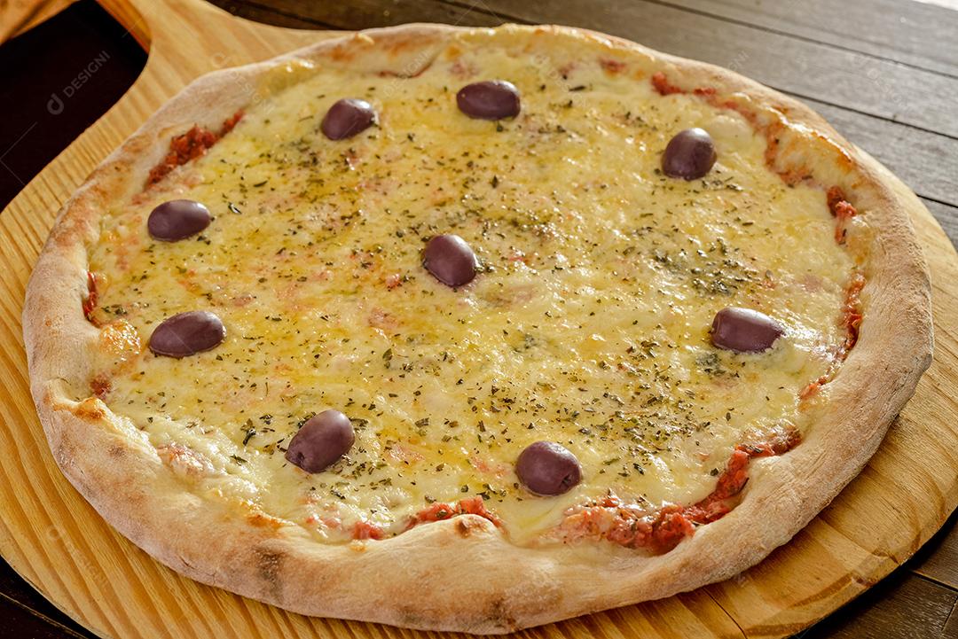 Pizza de camarão com azeitonas em close-up de pá de madeira.
