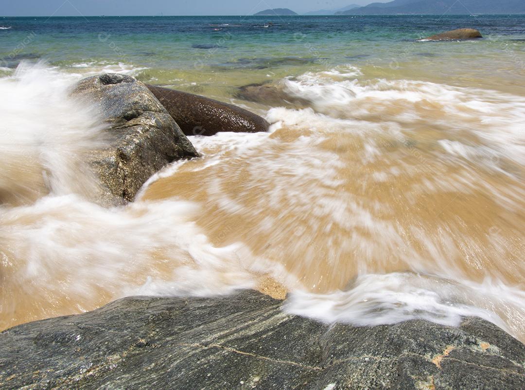 Onda borrada de movimento sobre uma praia rochosa na ilha de Ilhabela