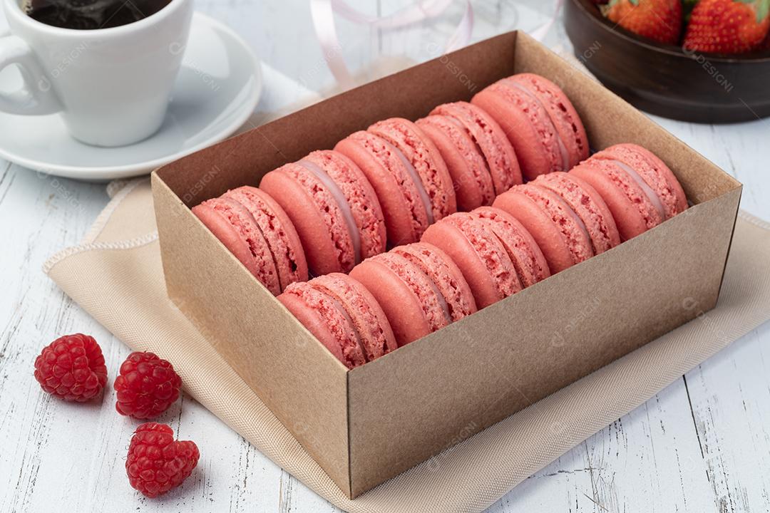 Macarons de Berry em uma caixa com café sobre a mesa de madeira