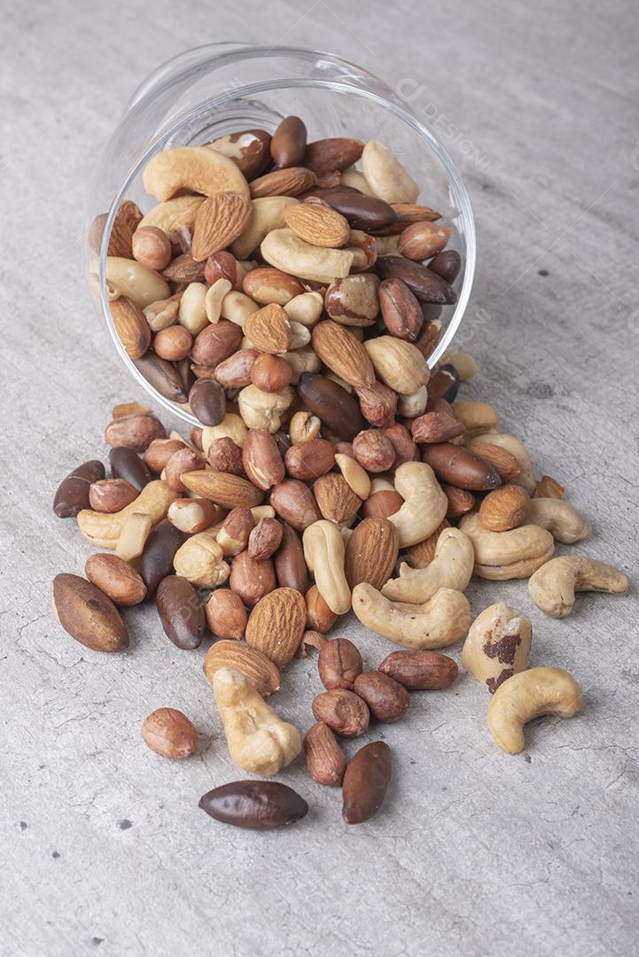 Tigela de vidro cheia de nozes mistas sobre um fundo de madeira. Amendoim