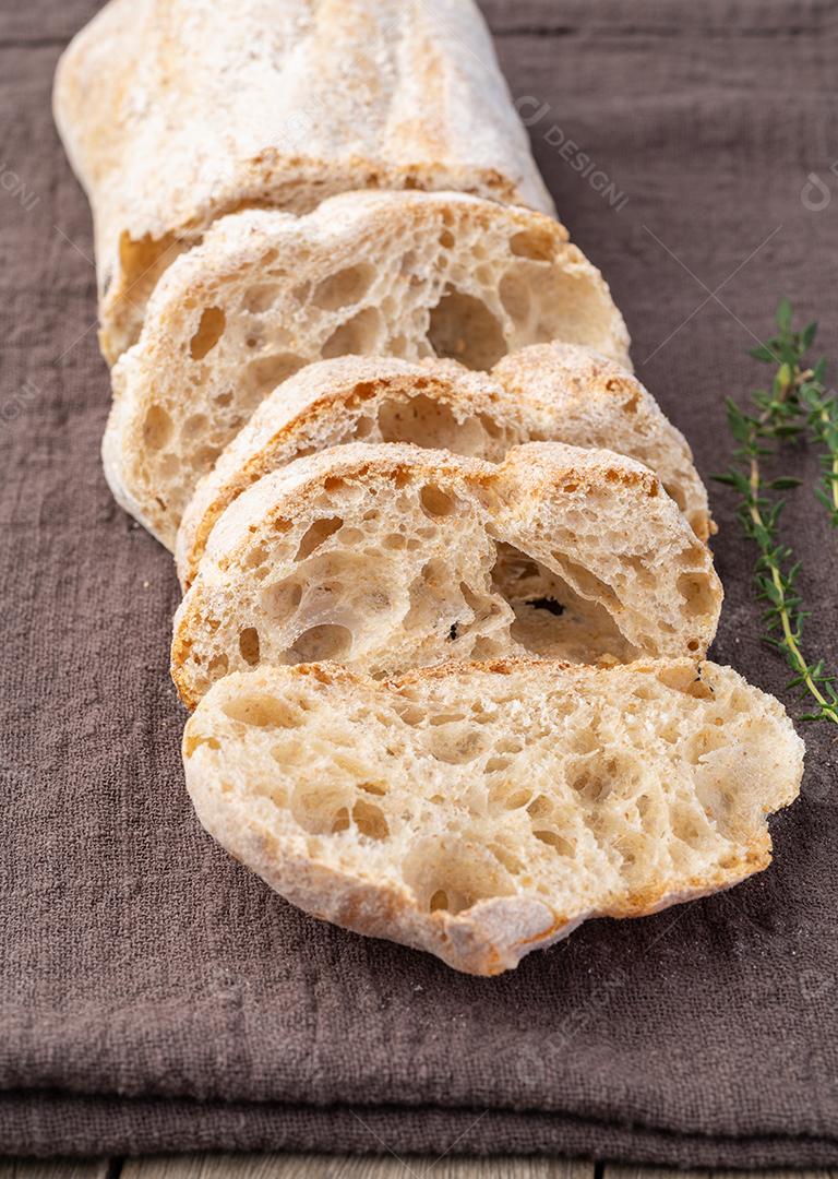 Pão ciabatta caseiro tradicional com fatias sobre tecido.