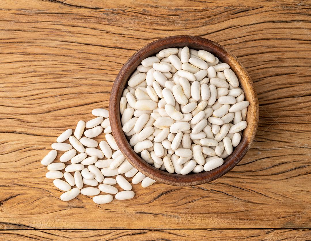 Feijão branco em uma tigela sobre a mesa de madeira.
