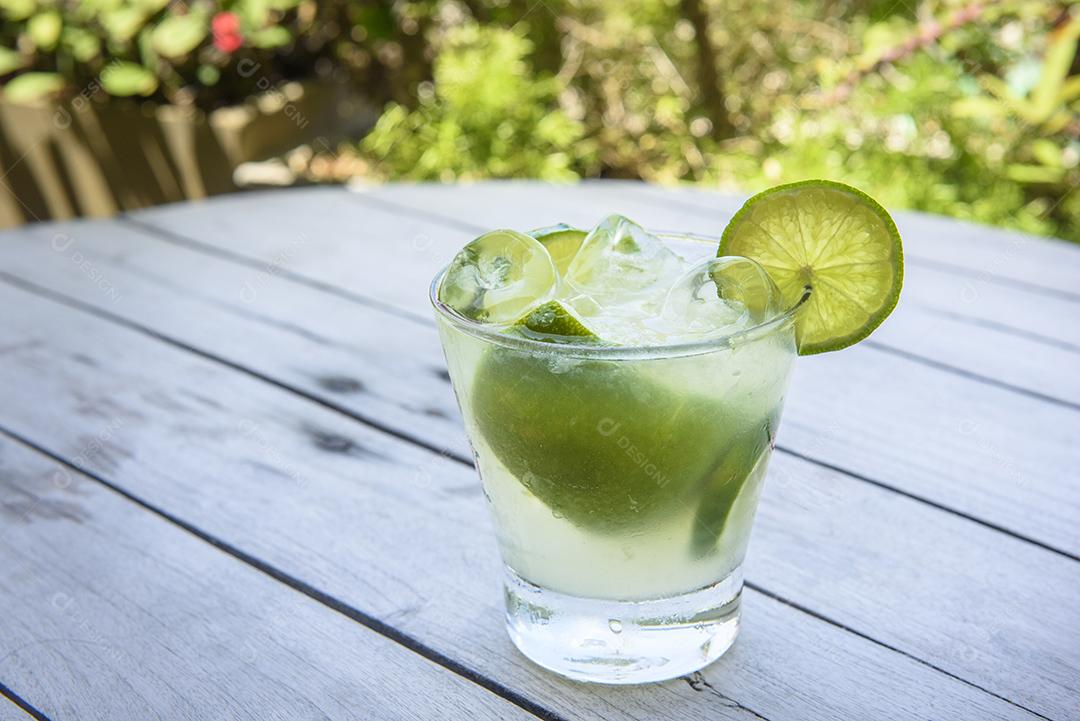 Bebida de caipirinha com limão em uma mesa de madeira envelhecida. Bebida típica