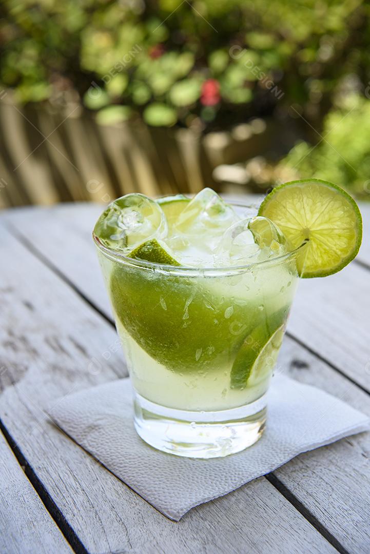 Bebida de caipirinha com limão em uma mesa de madeira envelhecida. Bebida típica