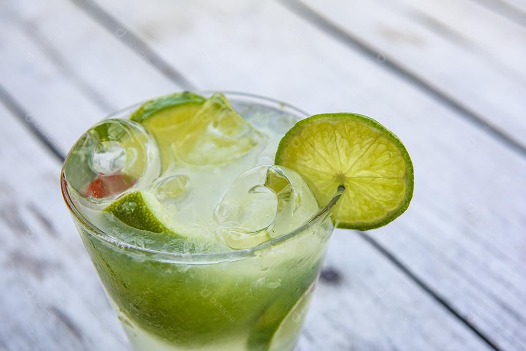 Bebida de caipirinha com limão em uma mesa de madeira envelhecida. Bebida típica