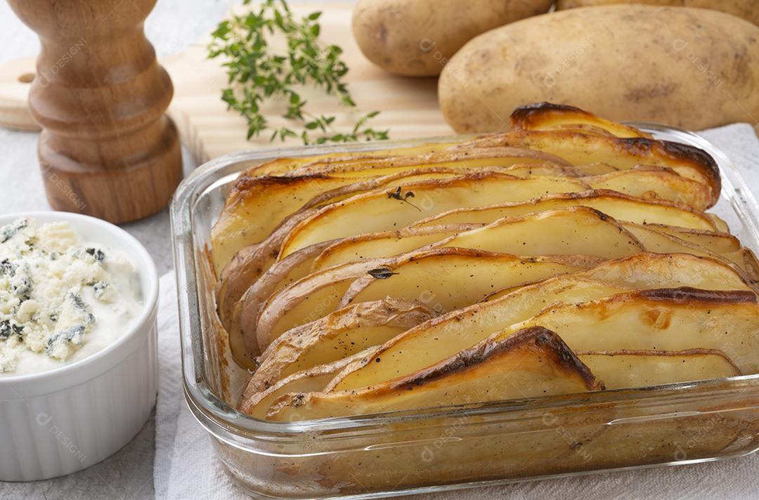Batatas fatiadas assadas com batatas cruas, temperos e molho de queijo azul.