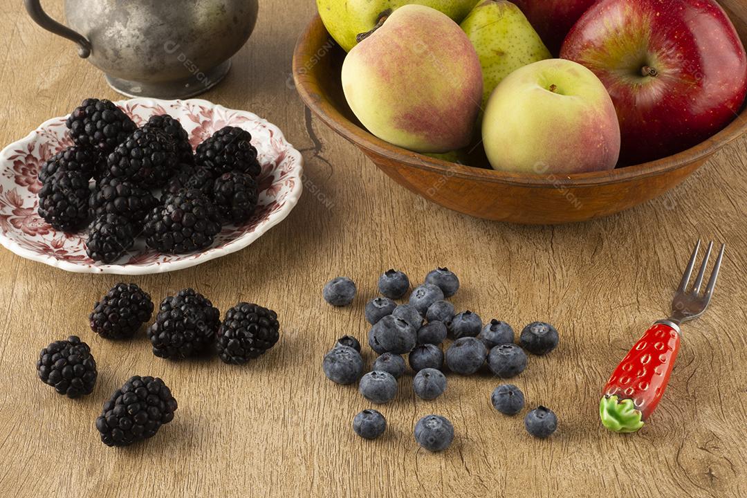 Frutas em uma tigela e bagas em um prato placa de madeira sobre uma mesa de madeira