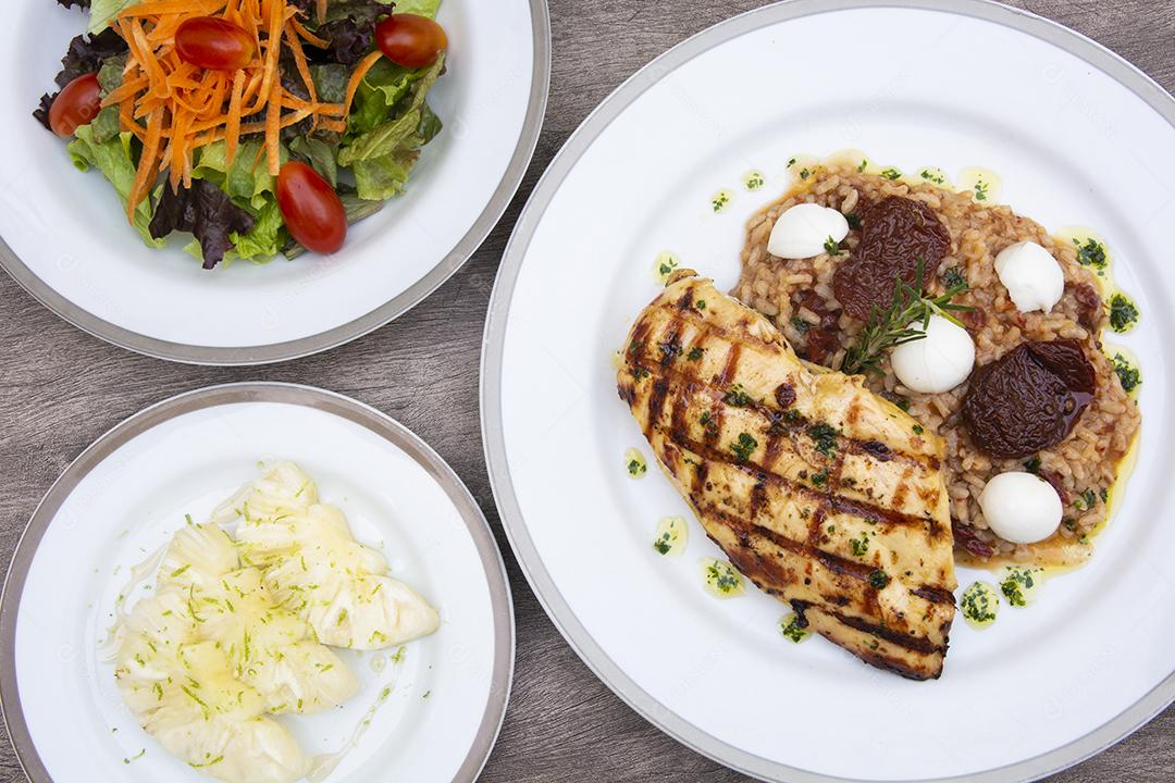 Frango grelhado, queijo e arroz de tomate, cenoura, alface e abacaxi fatiado em pratos