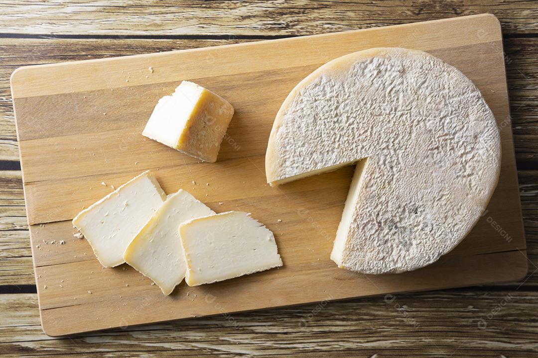 Queijo Canastra artesanal de Minas Gerais, Brasil sobre mesa de madeira.