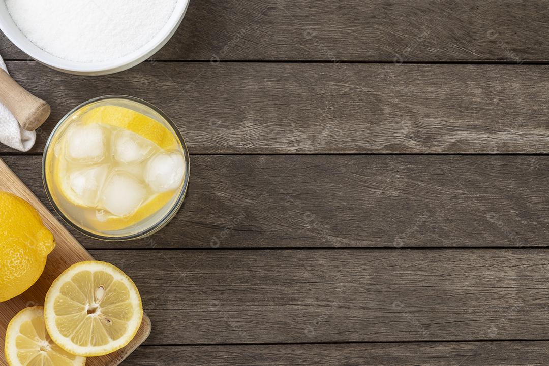 Caipirinha de limão brasileiro em um copo com gelo fatias de frutas sobre placa de madeira.