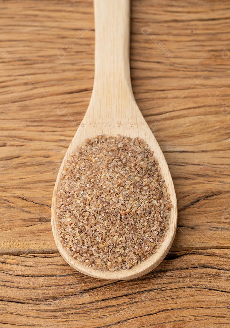 Trigo integral moído em uma colher sobre mesa de madeira