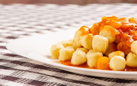 Nhoque de batata sem molho prato branco sobre toalha de mesa quadriculada preto e branco