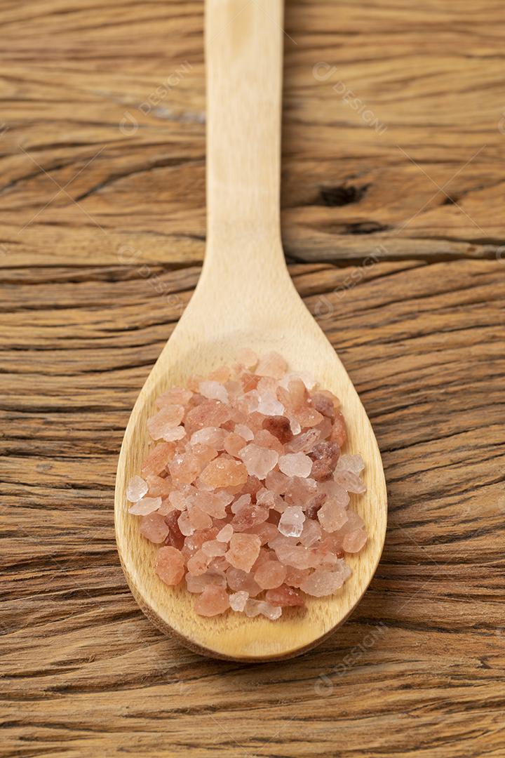 Sal rosa do Himalaia em uma colher sobre mesa de madeira